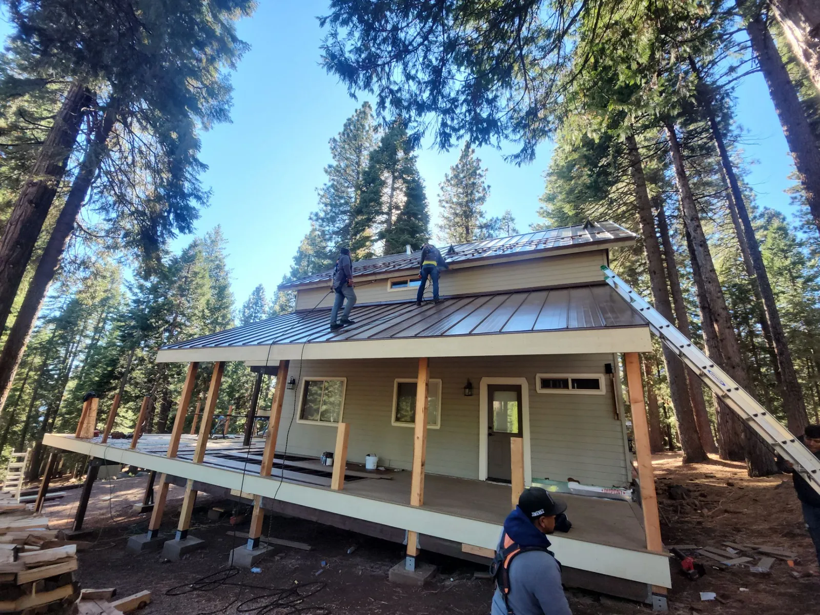 Butte Roofing crew installing a standing seam metal roof on a cabin in the pines above Chico