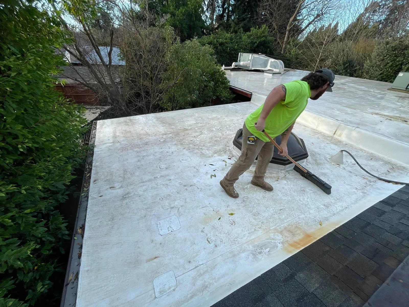 Butte Roofing crew member clearing leaves and debris from a commercial flat roof