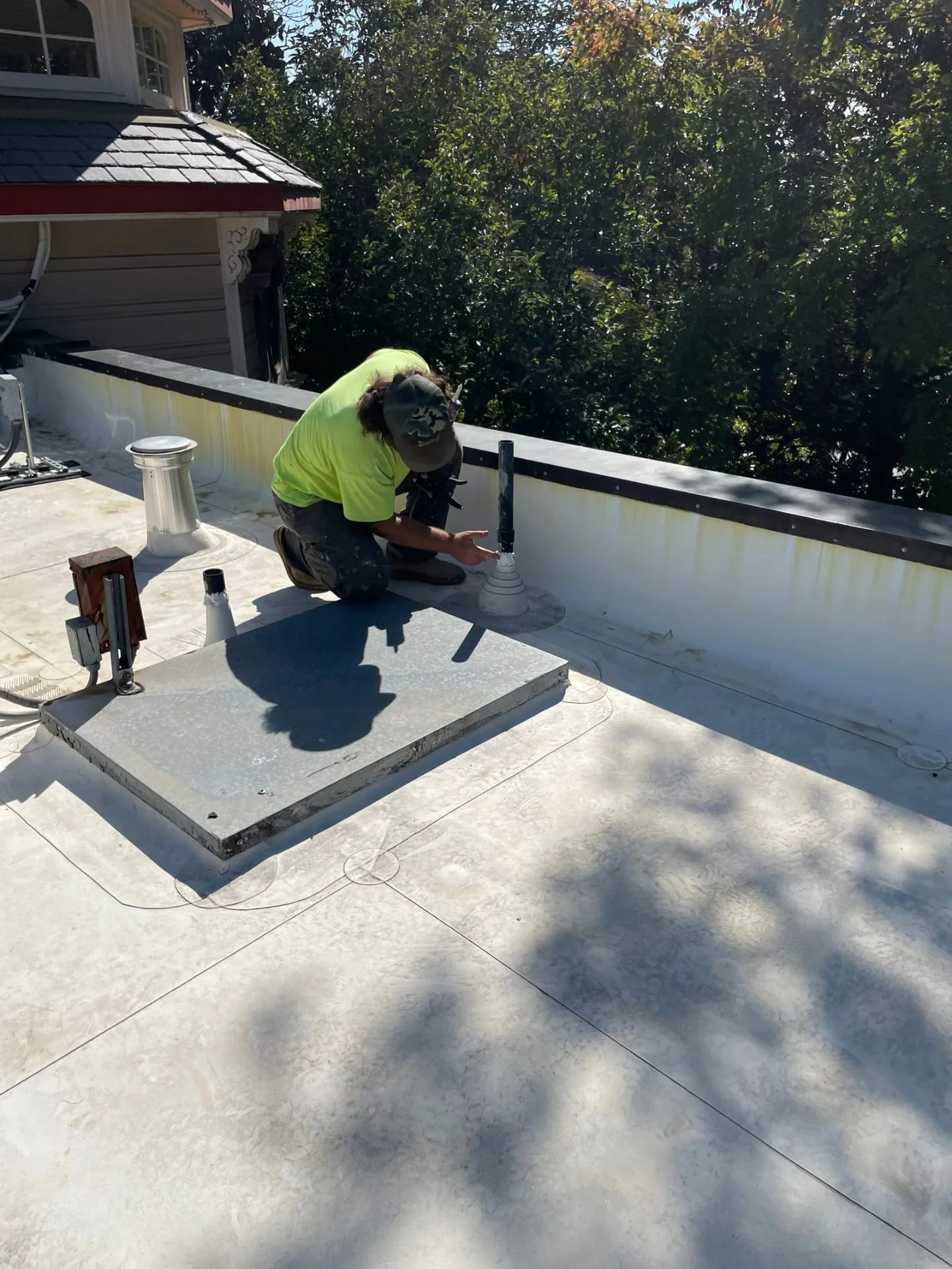 Butte Roofing crew member sealing the flashing at a pipe penetration on a commercial roof